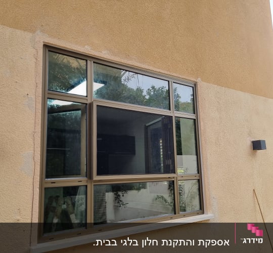 חלון אלומיניום עם מסגרת חומה על קיר חיצוני